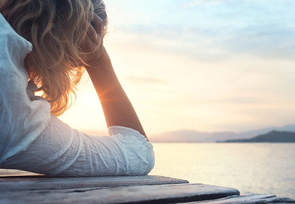 Woman lying on deck looking towards sun. Anxiety treatment