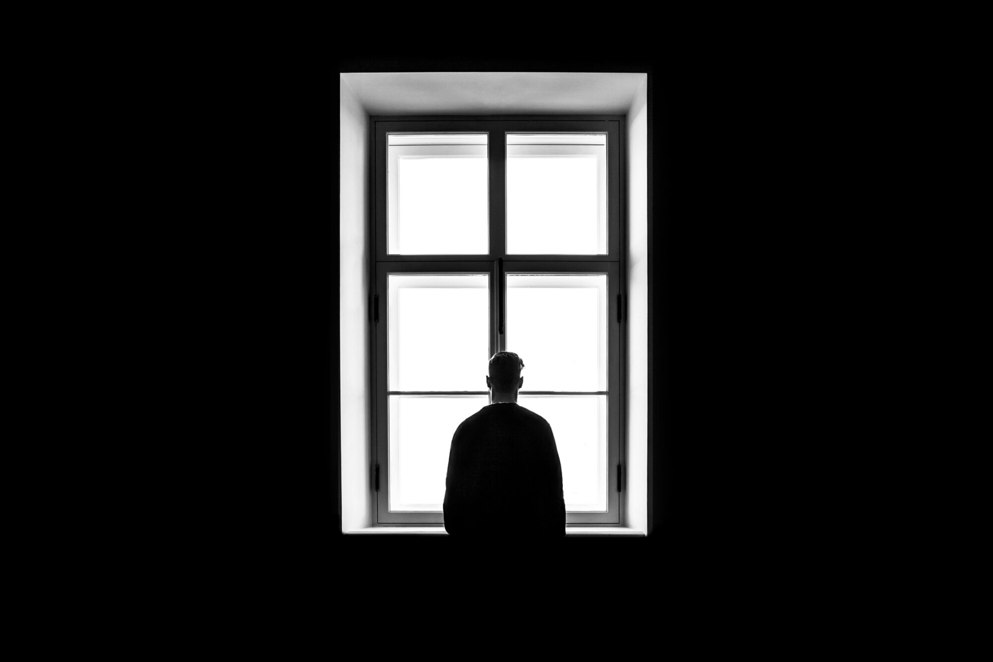 Rear view silhouetste man at window. Trauma, PTSD, anxiety