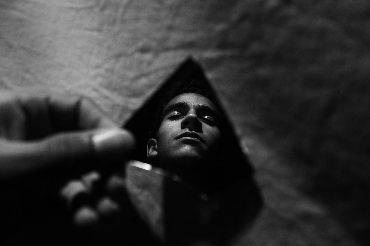 Man looking down into a small mirror. Social Anxiety Disorder