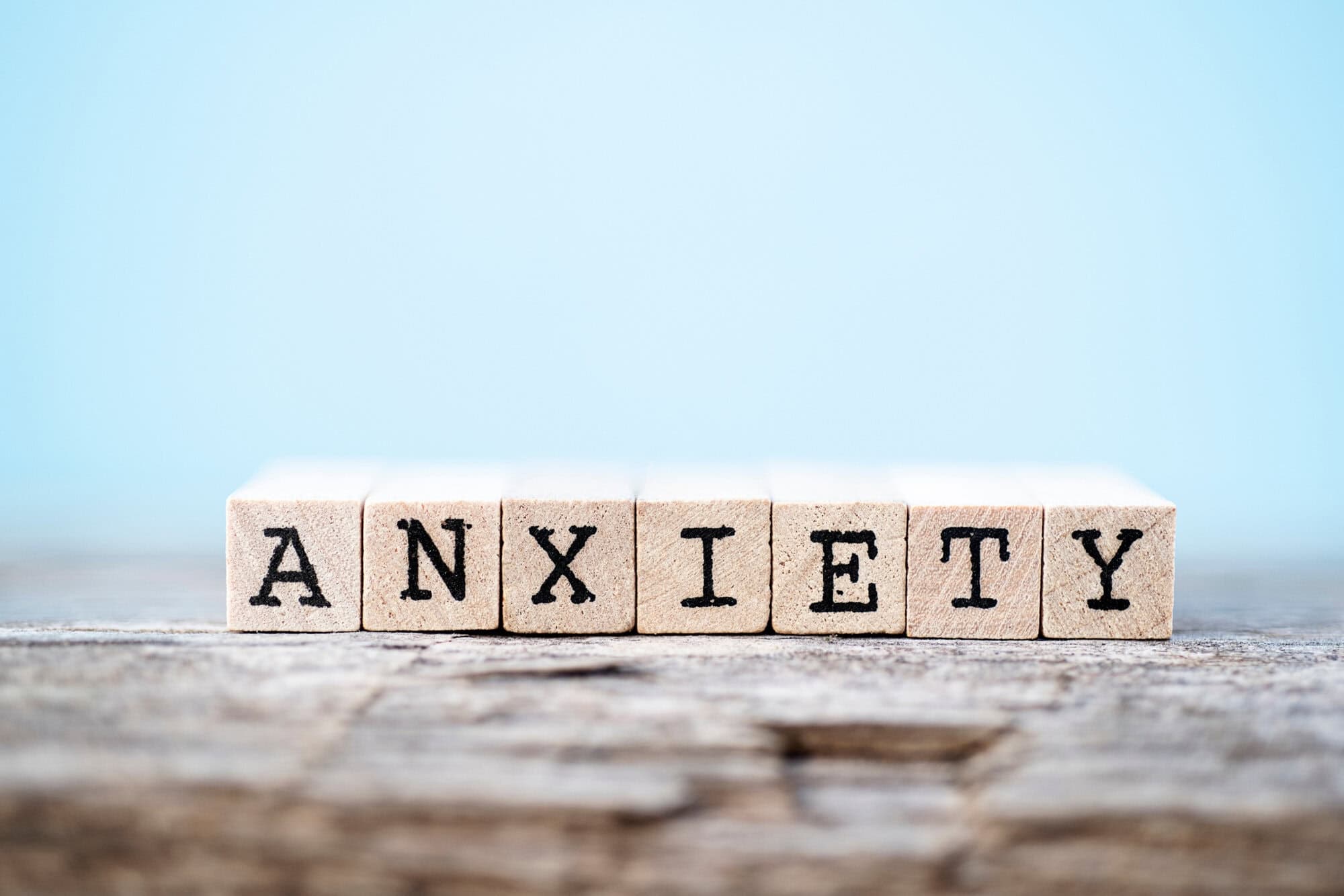 The word anxiety on wood with a light blue background